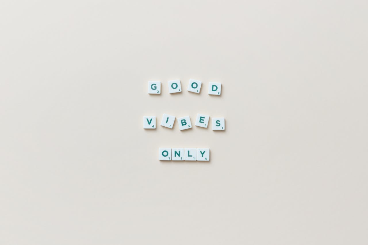 Flat lay of Scrabble tiles spelling 'Good Vibes Only' on a white background.